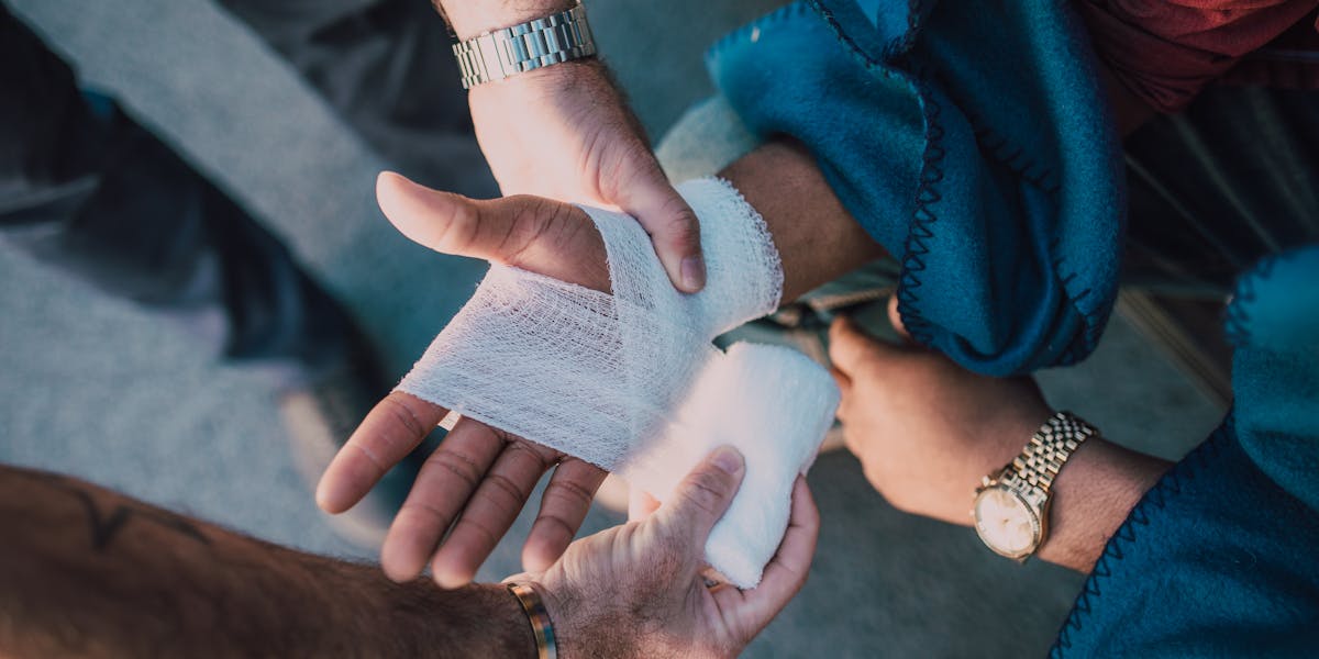 Paramedic bandaging an injured hand — first aid for knife wounds school guide